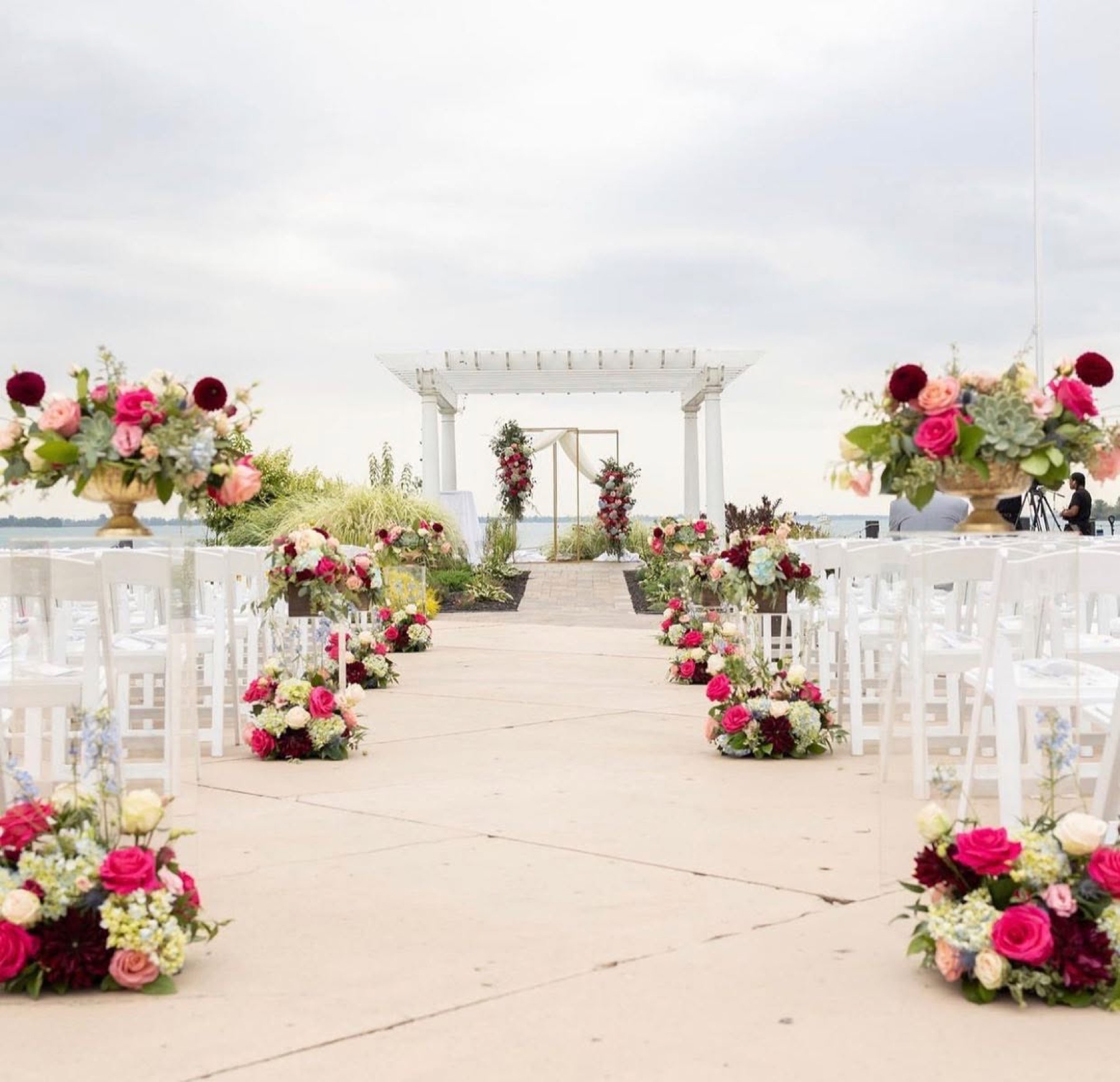 Ceremony chairs set in rows at the waterfront pergola, florals lining the aisle