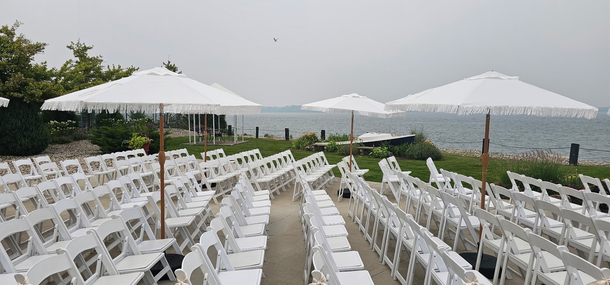 Rows of white ceremony chairs on the lawn facing open water