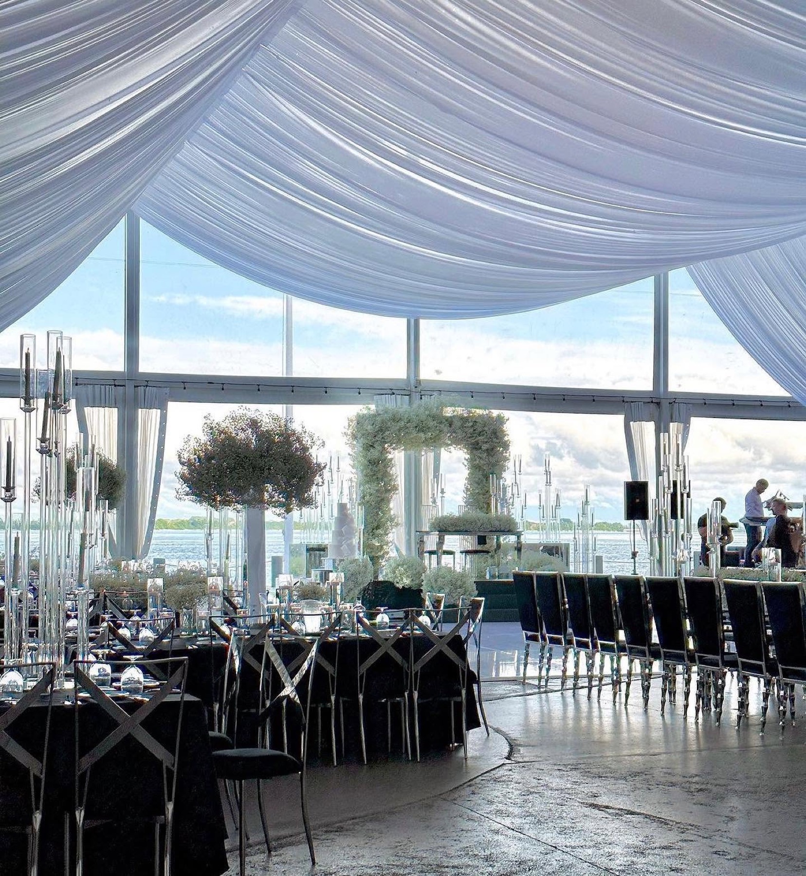 The ballroom set with dark linens and floor-to-ceiling views of the water