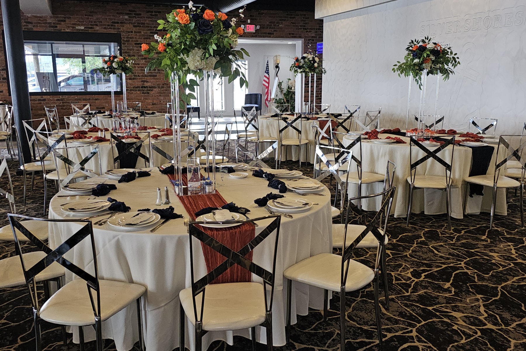 The indoor Ballroom with round tables and tall floral centerpieces