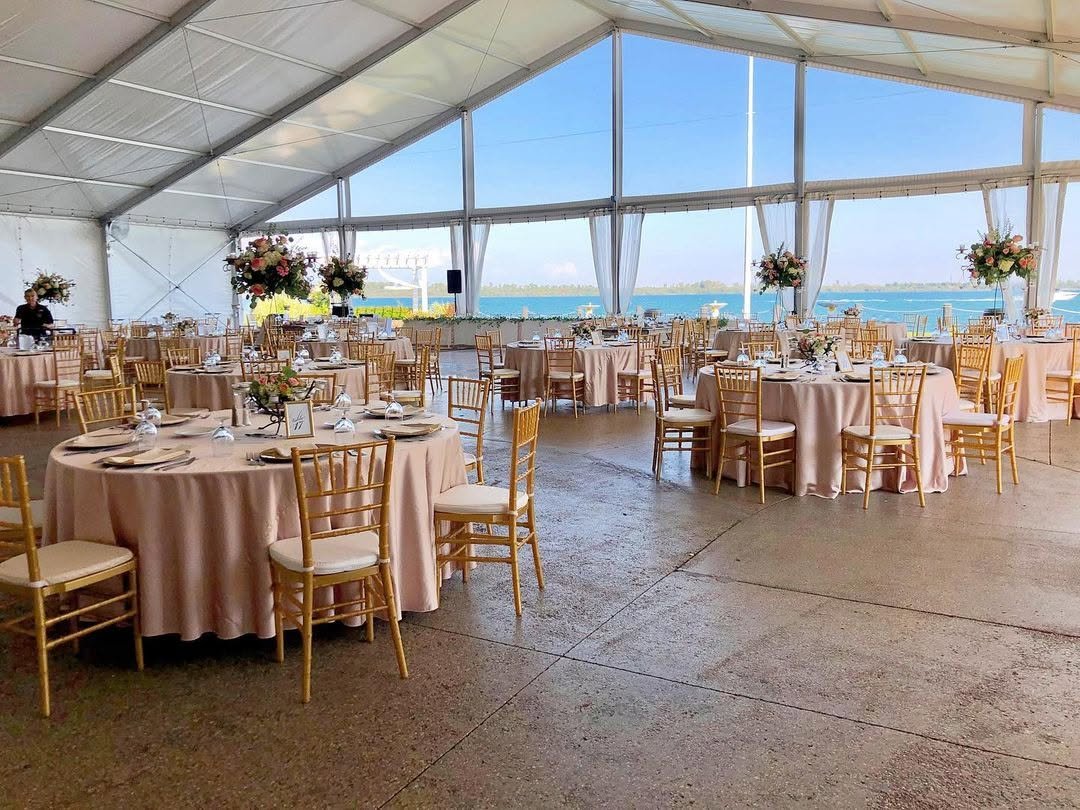 The riverside Pavilion set with gold chairs and open water through the glass wall